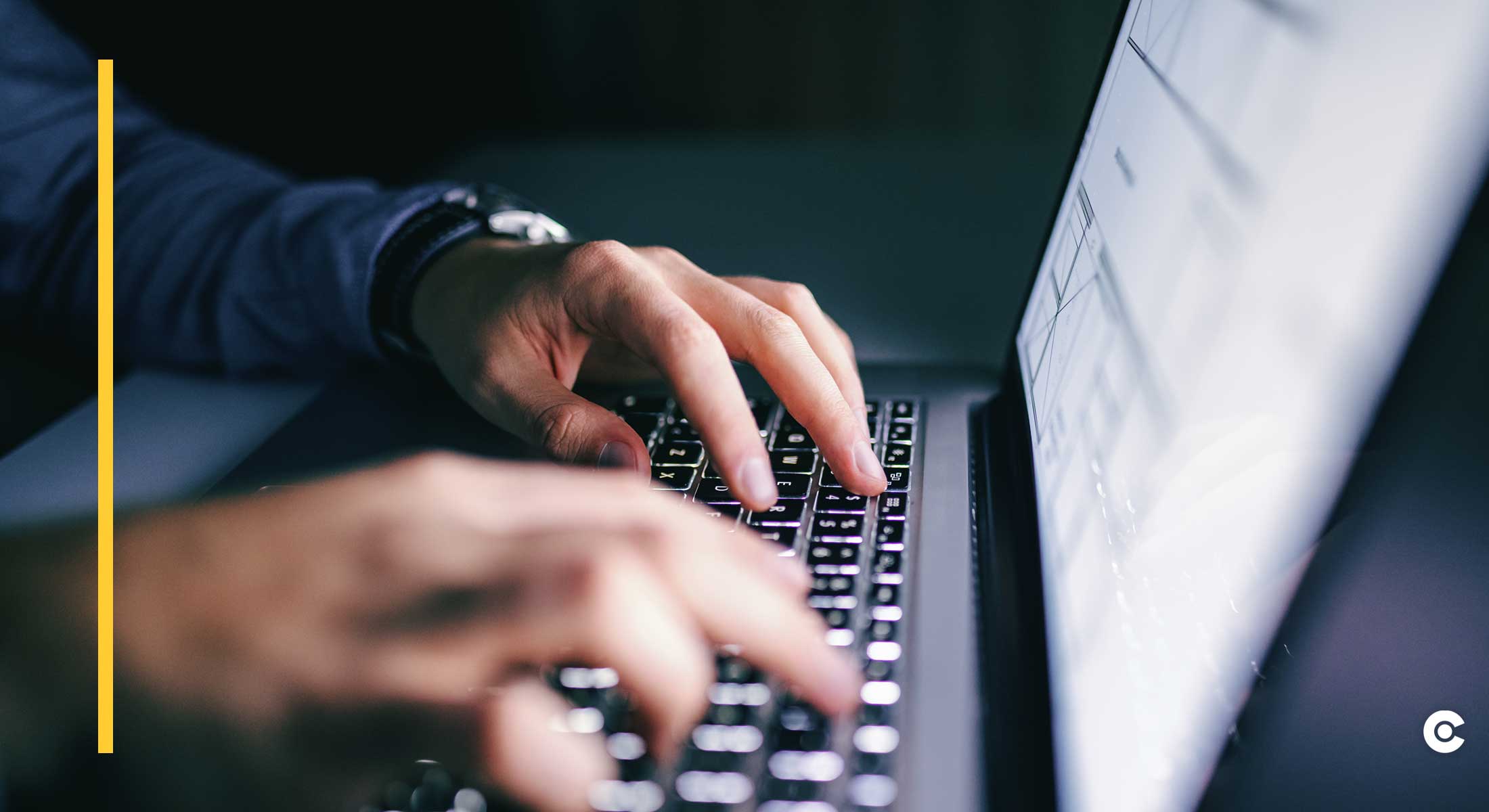 Hands typing on a dark, backlit keyboard