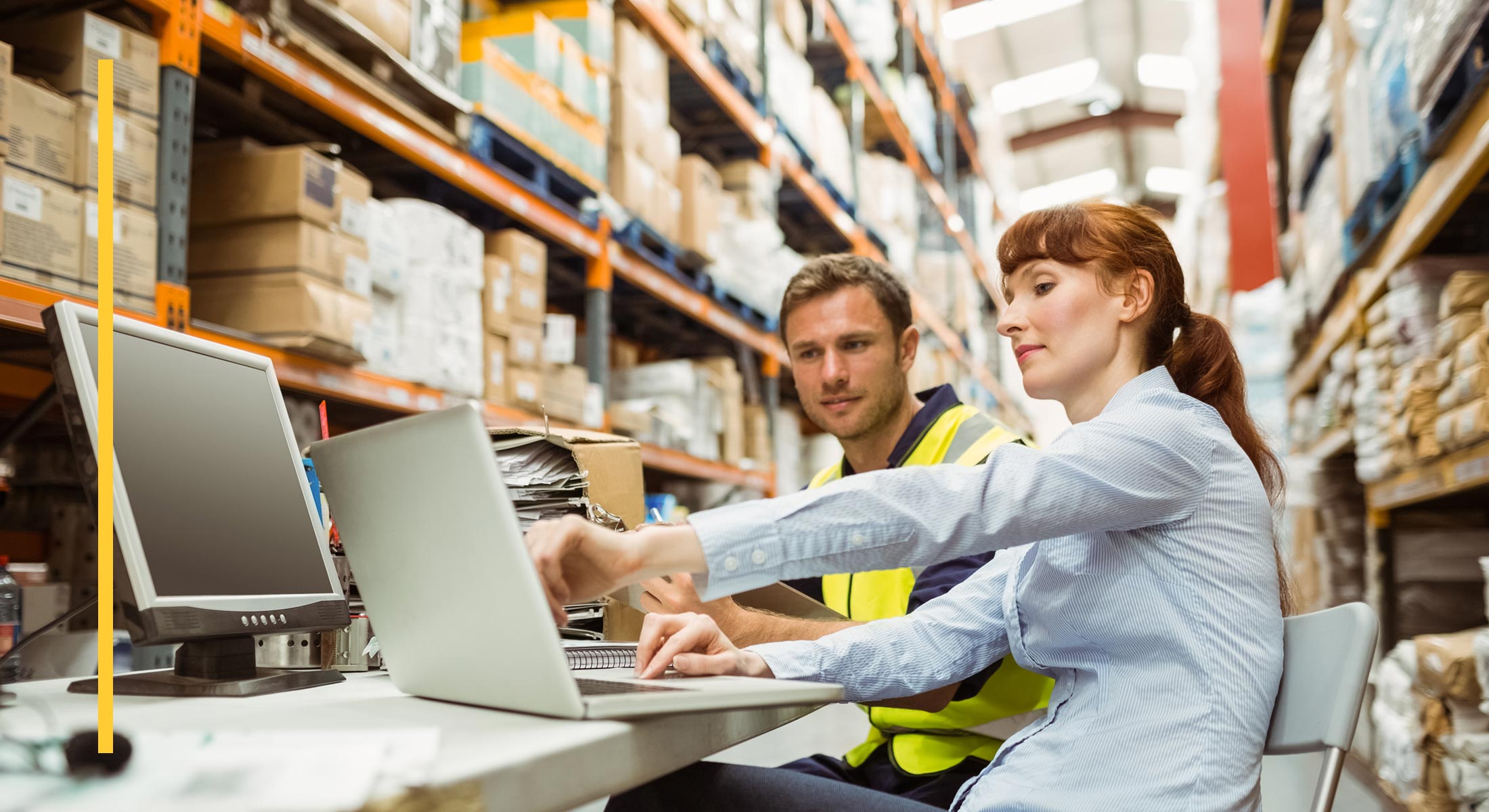Two people in a warehouse check details on a laptop for order management in Salesforce