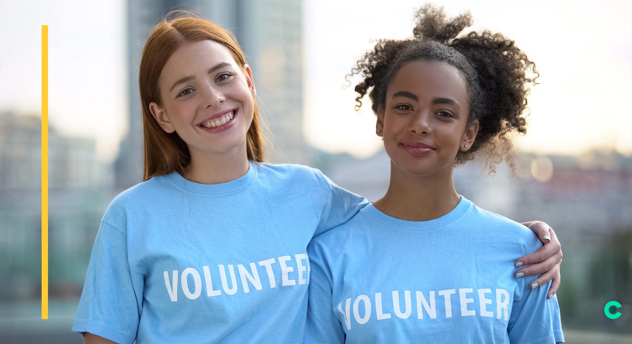 Two young woman are wearing blue shirts with "Volunteer" written on the front