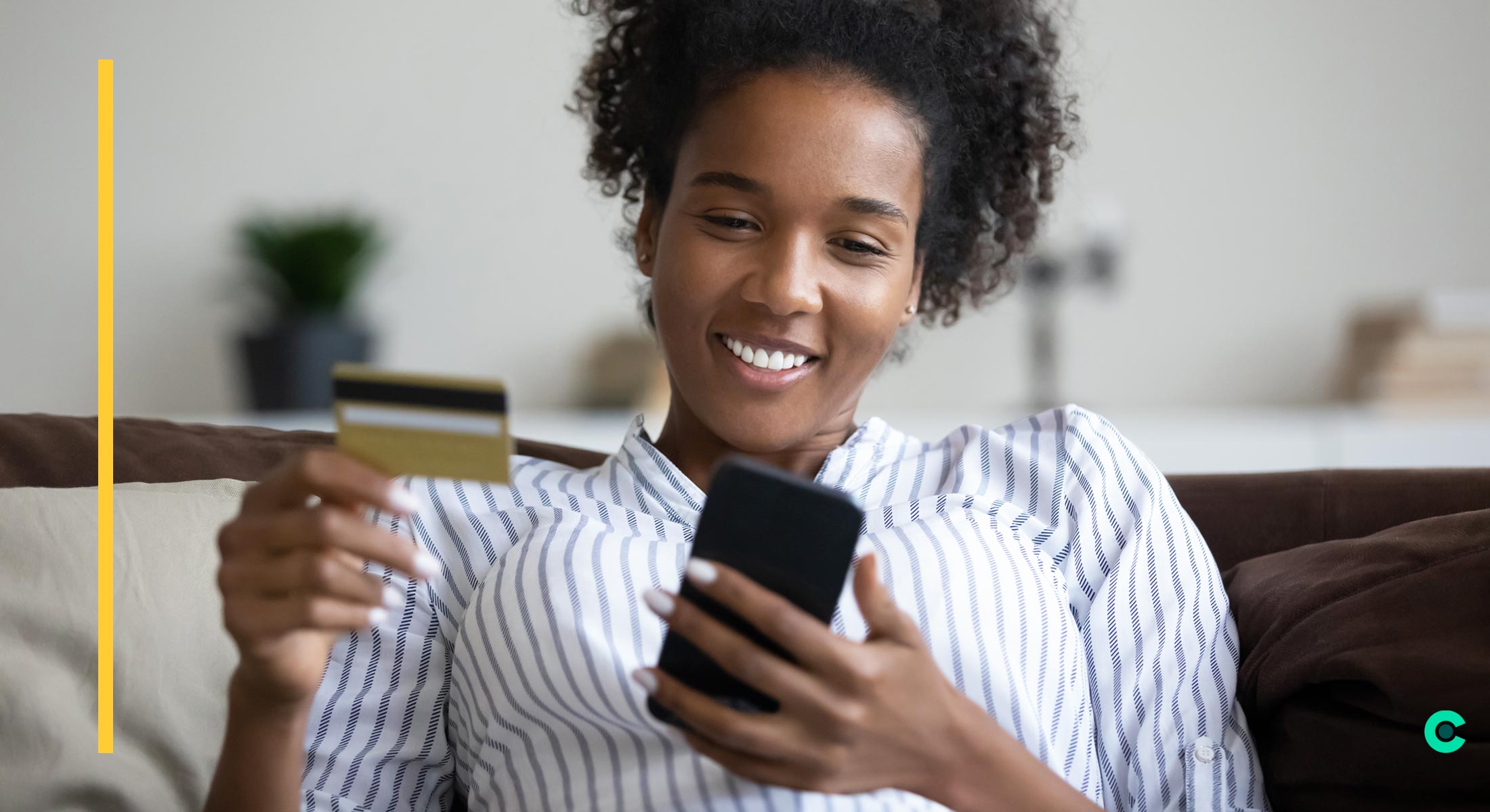 A woman holding a credit card happily pays a bill on her phone