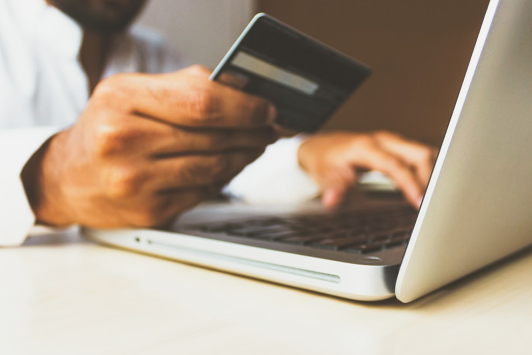 Person with a credit card in front of a laptop.