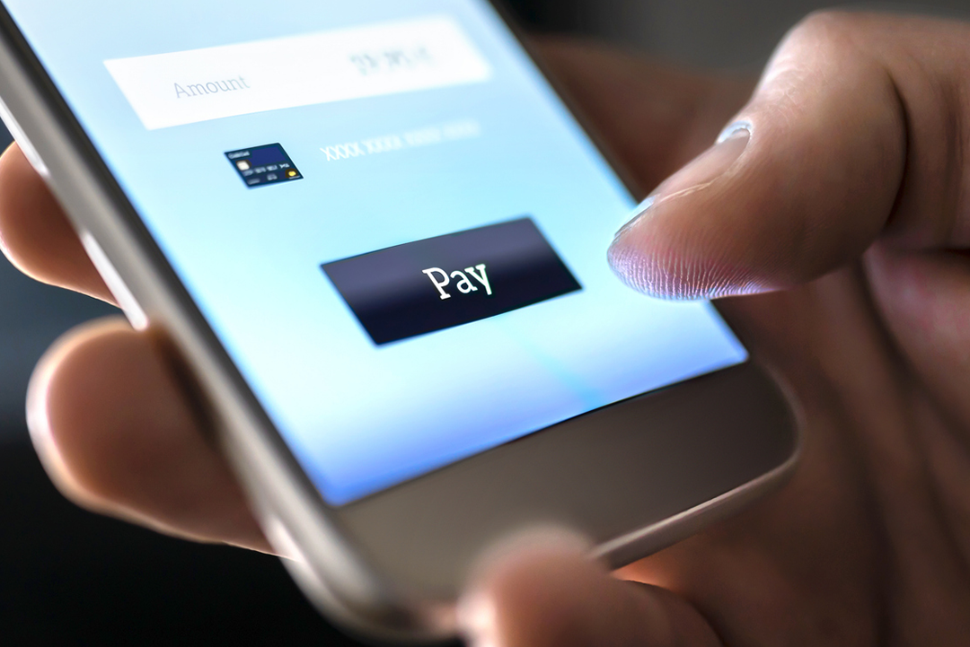 Person clicking 'pay' on a phone.